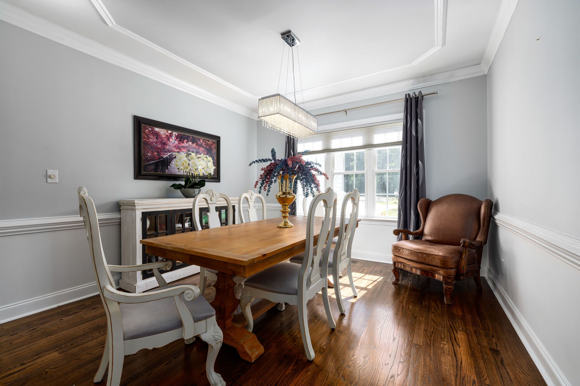 Bright dining room showcasing a wooden table, vintage chairs, and modern chandelier.